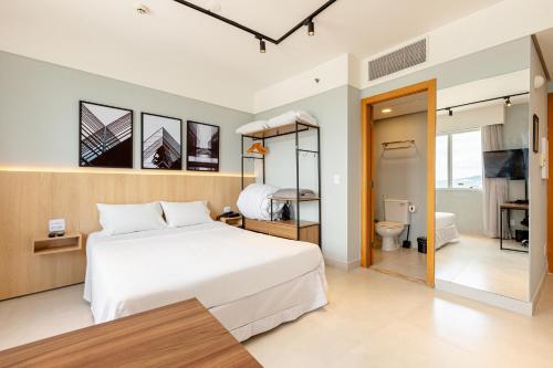 a bedroom with a large white bed and a bathroom at STD - Anora Spaces - Stadium Alphaville in Barueri