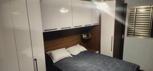 a small bedroom with a bed and white cabinets at Apê perto Alphaville in Osasco