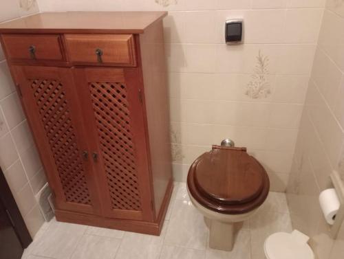 a bathroom with a toilet and a wooden cabinet at Apartamento in São Lourenço