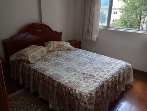 a bedroom with a bed with a quilt and a window at Apartamento in São Lourenço