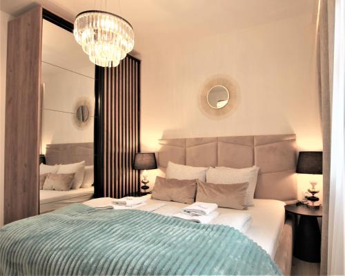 a bedroom with a bed and a chandelier at Grand Royal Baltic Ustka - luksusowy Apartament 150 metrów od plaży, port, zielony taras, bezpłatny parking, top lokalizacja w centrum Ustki in Ustka