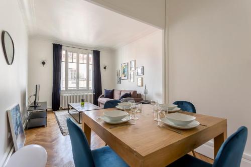 une salle à manger avec une table en bois et des chaises bleues dans l'établissement Hamac Suites - Suite Crillon, à Lyon