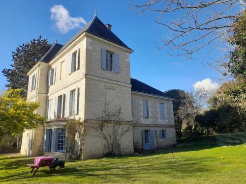 un chien assis sur un banc devant un bâtiment dans l'établissement Gite au château, à Castelnau-sur-Gupie