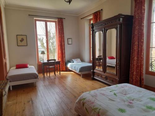 une chambre avec deux lits et un grand miroir dans l'établissement Gite au château, à Castelnau-sur-Gupie