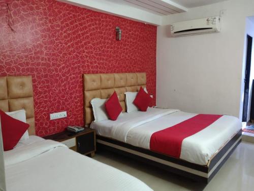 - une chambre avec 2 lits et un mur rouge dans l'établissement Hotel Anjali palace, à Ahmedabad