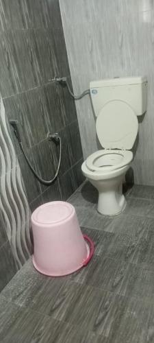 La salle de bains est pourvue de toilettes et d'un seau rose. dans l'établissement Hotel Anjali palace, à Ahmedabad