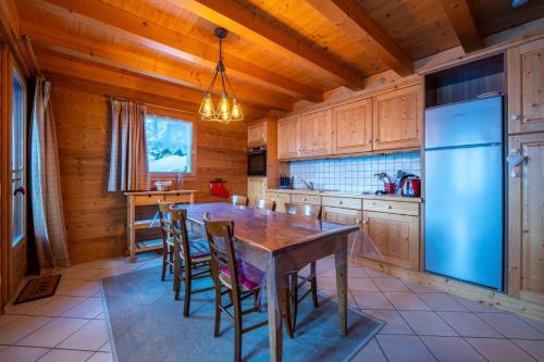une cuisine avec une table, des chaises et un réfrigérateur dans l'établissement Cosymontagne - Le Chalet - 3Ch - 8 pers- Terrasse Sud, magnifique vue, à La Clusaz