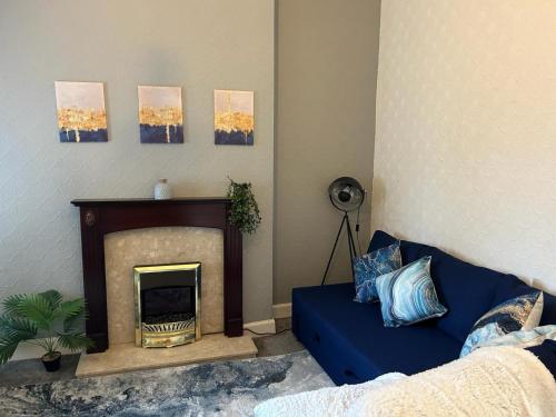 a living room with a blue couch and a fireplace at Bute Apartment by Klass Living Coatbridge in Coatbridge
