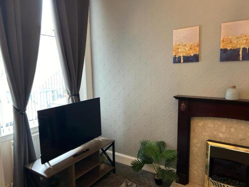 a living room with a flat screen tv and a fireplace at Bute Apartment by Klass Living Coatbridge in Coatbridge