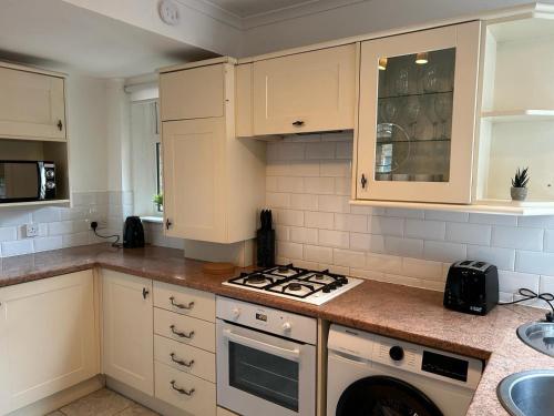 a kitchen with white cabinets and a stove top oven at Bute Apartment by Klass Living Coatbridge in Coatbridge