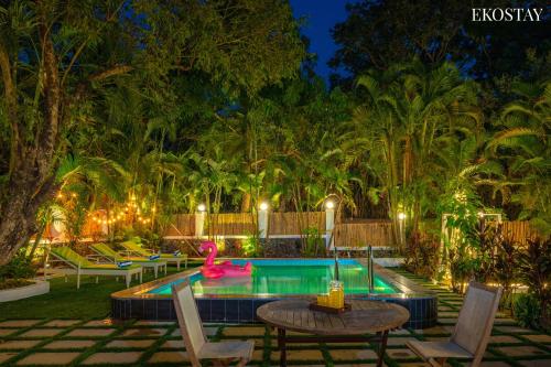 a pool with a table and chairs next to a resort at Ekostay Luxe - CASA SIA - Ideal for Big Groups- Poker Table in Lonavala