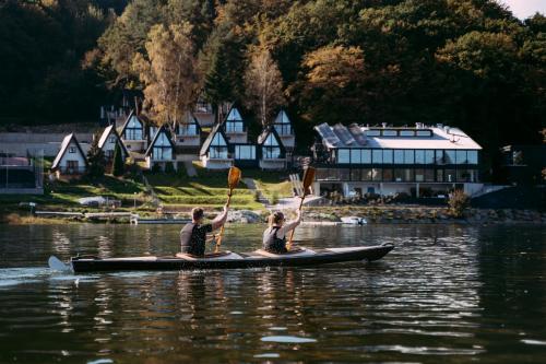 two people on a paddle board on the water at NOI Resort SPA - woda i las in Tęgoborze