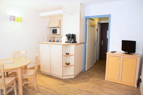 Il comprend une petite cuisine et une salle à manger avec une table. dans l'établissement Résidence Promenade des Bains - maeva Home - Studio 4 Personnes - Confort MAE-2294, à Saint-Raphaël