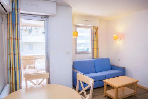 un salon avec un canapé bleu et une table dans l'établissement Résidence Promenade des Bains - maeva Home - Studio 4 Personnes Confort MAE-2296, à Saint-Raphaël