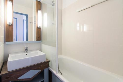 une salle de bain blanche avec un lavabo et une baignoire dans l'établissement Résidence Port Bourgenay - maeva Home - Studio 5 Personnes Sélection MAE-2311, à Talmont-Saint-Hilaire