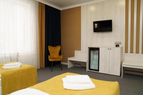 una camera d'albergo con due letti e una TV a parete di BURSA a Taraz
