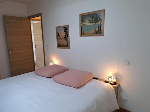 - une chambre avec un lit blanc et 2 oreillers roses dans l'établissement Appartement cosy 2 chambres - 300m de la plage, à Biscarrosse