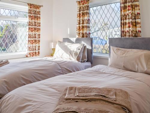 two beds in a bedroom with two windows at Crosslands in Penrith