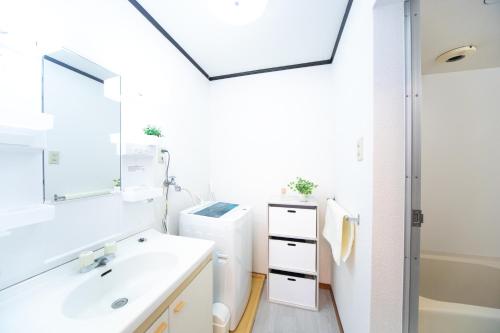 Baño blanco con lavabo y espejo en Suzuka Smile Room en Suizawa
