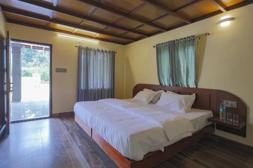 ein Schlafzimmer mit einem großen Bett und einem großen Fenster in der Unterkunft Vineyard Homestay in Santhanpara