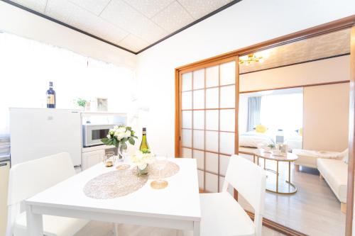 a white dining room with a white table and chairs at Suzuka Smile Room in Suizawa