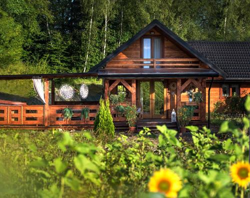 een blokhut met een veranda en een tuin bij DOMEK KARMELOWY - Azyl Na Szwedach in Ruszelczyce