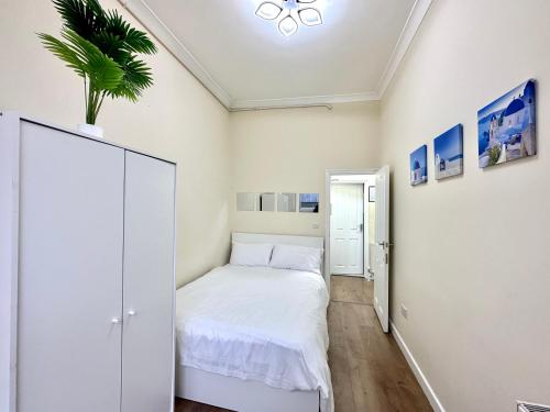 ein kleines Schlafzimmer mit einem weißen Bett und einer Pflanze in der Unterkunft The Euston Guest House-64 in London