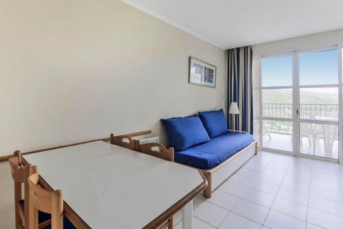 un salon avec un canapé bleu et un balcon dans l'établissement Résidence le Village de Cap Esterel - maeva Home - Studio 5 Personnes - Confort MAE-2363, à Saint-Raphaël
