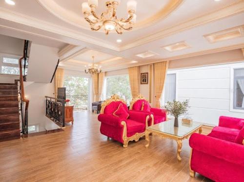 a living room with two red chairs and a table at Villa Đà Lạt View Thông in Khu Chi Lăng