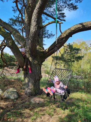 two dolls sitting on a swing in a tree at Siedlisko13 in Mrągowo