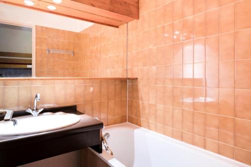 une salle de bain avec un lavabo et une baignoire dans l'établissement Résidence Les Fontaines Blanches - maeva Home - Studio 4 Personnes Budget MAE-3635, à Morzine