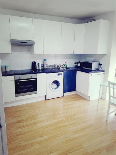 a kitchen with white cabinets and a washing machine at Double Room Close To Headingley Stadium Leeds in Leeds