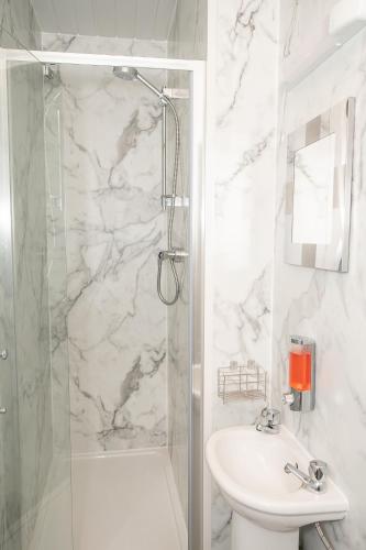 a white bathroom with a shower and a sink at The Wheeldale in Whitby