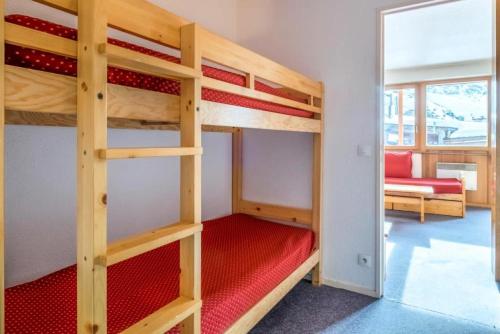 Cette chambre comprend 2 lits superposés avec un banc rouge. dans l'établissement Résidence Les Fontaines Blanches - maeva Home - Studio 4 Personnes Budget MAE-3721, à Morzine