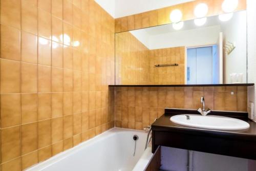 une salle de bain avec un lavabo, une baignoire et un miroir dans l'établissement Résidence Les Fontaines Blanches - maeva Home - Studio 4 Personnes Budget MAE-3721, à Morzine