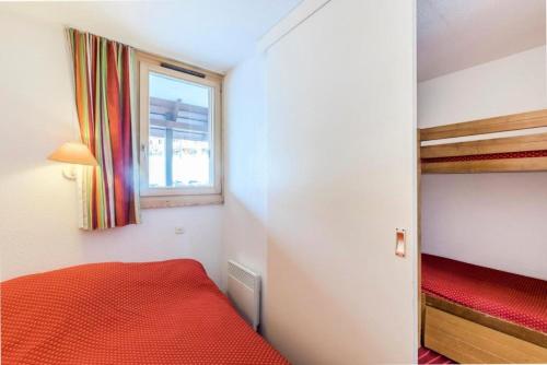 Cette petite chambre comprend un lit rouge et une fenêtre. dans l'établissement Résidence Les Fontaines Blanches - maeva Home - 2 Pièces 6 Personnes Confort MAE-3722, à Morzine