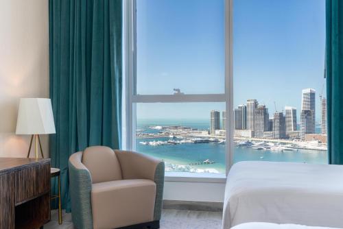 um quarto de hotel com uma cama e uma cadeira e uma janela em 2BR Avani Palm View - CityApartmentStay no Dubai