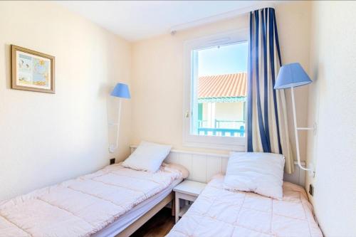 deux lits dans une chambre avec une fenêtre dans l'établissement Résidence Port Bourgenay - maeva Home - 2 Pièces 4 Personnes Sélection MAE-5309, à Talmont-Saint-Hilaire