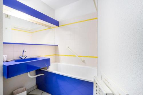La salle de bains est pourvue d'un lavabo bleu et d'une baignoire. dans l'établissement Résidence Port du Crouesty - maeva Home - Studio 5 Personnes - Confort MAE-5431, à Arzon