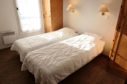 duas camas num quarto de hotel com lençóis brancos em Résidence Le Grand Panorama - 3 Pièces pour 6 Personnes 56 em Saint-Gervais-les-Bains