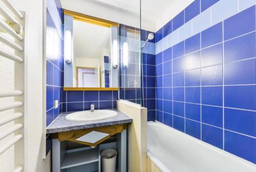 a blue tiled bathroom with a sink and a tub at Le Cap Glénan - maeva Home - 2 Pièces 5 Personnes Confort MAE-5638 in Bénodet