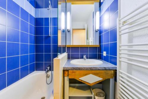ein blau gefliestes Badezimmer mit Waschbecken und Badewanne in der Unterkunft Le Cap Glénan - maeva Home - 2 Pièces 5 Personnes Confort MAE-5640 in Bénodet