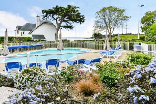 une piscine avec des chaises bleues et des parasols dans l'établissement Le Cap Glénan - maeva Home - 2 Pièces 5 Personnes Confort MAE-5648, à Bénodet