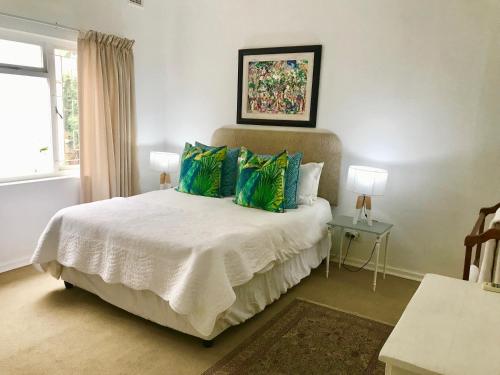 a bedroom with a white bed with green pillows at Sagelands for business travel & family getaways in Durban