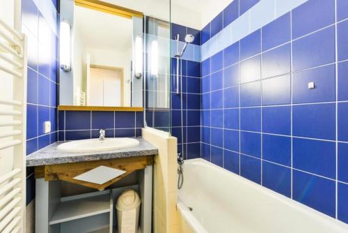 a blue tiled bathroom with a sink and a tub at Le Cap Glénan - maeva Home - 2 Pièces 5 Personnes Sélection 39 in Bénodet