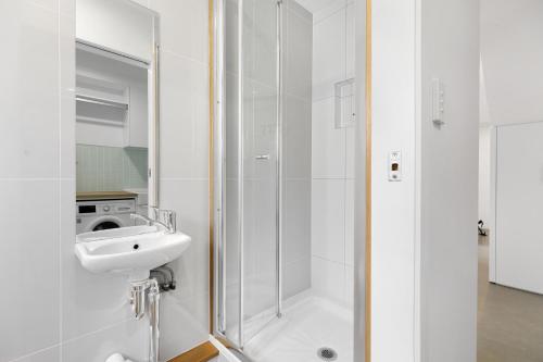 y baño blanco con lavabo y ducha. en Charming 5-Bed Coastal Escape in Maroochydore en Maroochydore