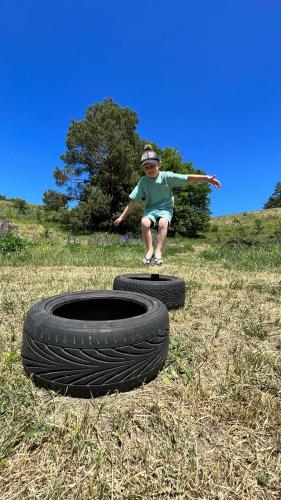 a young boy standing on two tires in a field at Siedlisko13 in Mrągowo