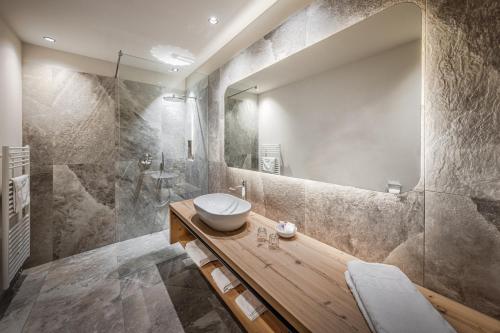 y baño con lavabo y espejo. en Hotel Alpenrose Dolomites, en La Valle