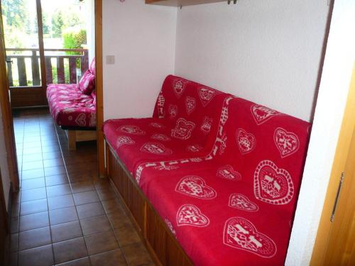 Cette chambre dispose d'un balcon et d'un canapé rouge. dans l'établissement Résidence Perle Des Neiges - Perles des Neiges 1 MAE-5319, à Combloux