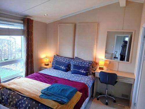 um quarto com uma cama com almofadas azuis e uma secretária em 19 Park Views Just outside Penrith for Holidays and Short Breaks please no commercial vans thankyou em High Hesket